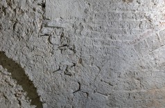 gemauerte Wand, in der sich Bögen und verschieden große Tuffsteine und Ziegel abzeichnen