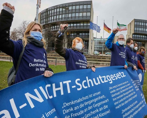 Protestierende Bürger*innen mit "Rettet den Denkmalschutz in NRW"-T-Shirts und Banner "Denkmal-Nicht-Schutz-Gesetz"